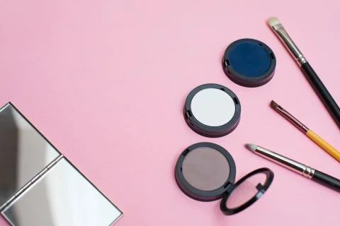 A make-up set on a pink background: makeup brushes, eyeshadows, and a mirror Stock Photos