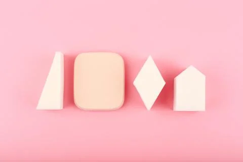 Make up sponges of different shapes on bright pink background Stock Photos
