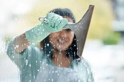 Make sure your squeegee is clean. a young woman cleaning her windows. Stock Photos