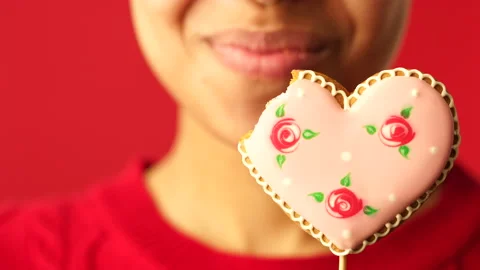 Make sweet memories. Close up of young girl biting a delicious heart shaped Stock Footage 146129591