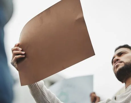 Make them hear you. Low angle shot of a handsome young man holding a sign while Stock Photos