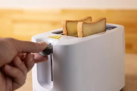 To make toast, bread is loaded into an electric Stock Photos