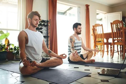 Make your home a mindful zone. two young men using a laptop while meditating in Stock Photos