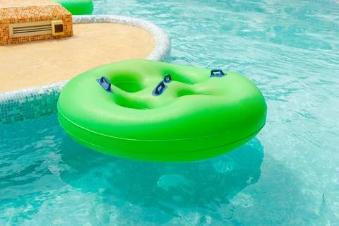 Make your summer more enjoyable by relaxing in the pool with a green inflatable Stock Photos