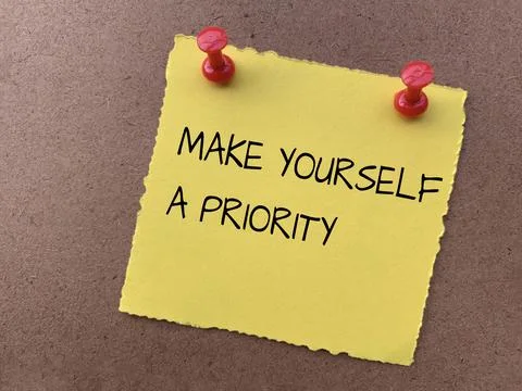 Make yourself a priority text on yellow notepad with wooden background. Motiv Stock Photos