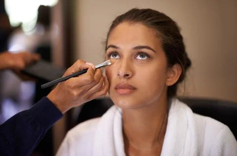 Makeover time. Shot of an attractive young woman having makeup applied to her Stock Photos