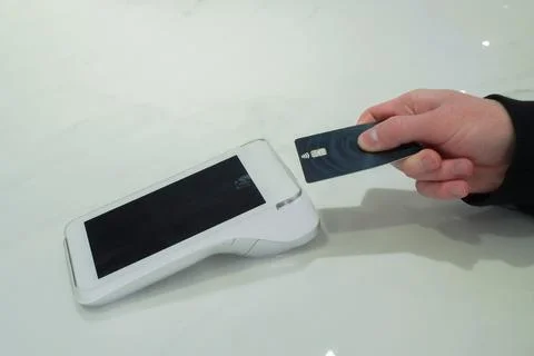Makes a contactless payment by tapping a debit card using a digital terminal Stock Photos