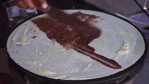Makes a crepe pancake on a baking tray in a creperie, give chocolate topping 库存影片 204048844
