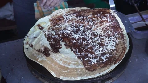 Makes a crepe pancake on a baking tray in a creperie, give chocolate topping 库存影片 204048847