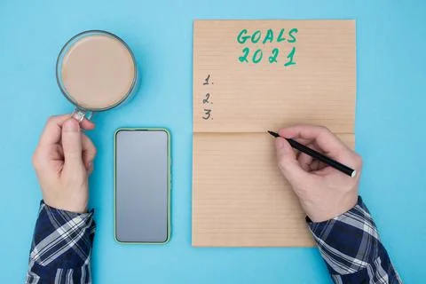 Makes a to do list for the new year 2021 and drinks coffee. Man sets goals for Stock Photos