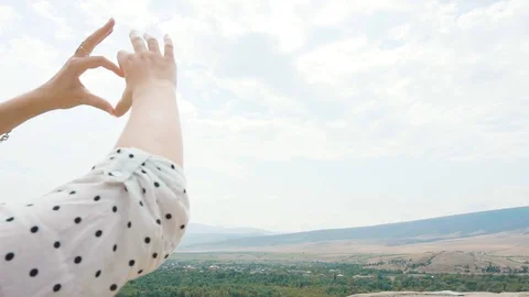 Makes a heart shape out of her fingers, a young attractive woman with blond hair Stock Footage 105968771