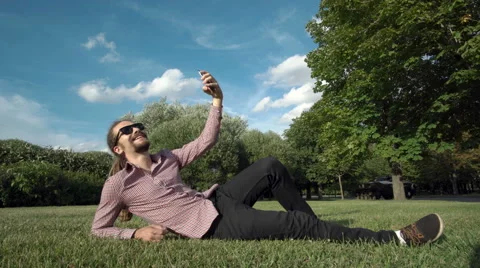 Makes selfie in a public park: smart phone, photo Video stock 65035333