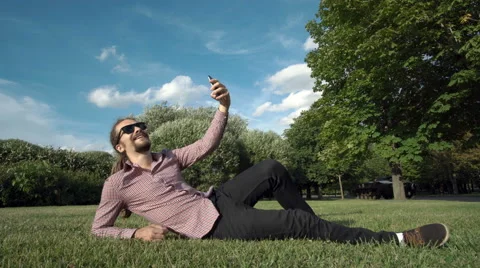 Makes selfie in a public park: smart phone, photo Vídeo Stock 65035944