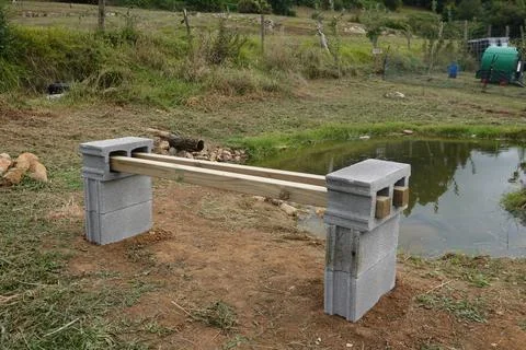 A makeshift bench made from concrete blocks and a wooden plank, placed near.. Stock Photos