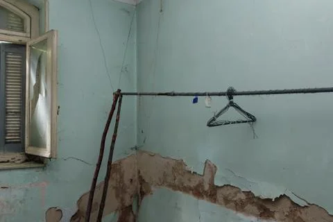 Makeshift clothesline with rusty hangers in decayed blue room Stock-Fotos