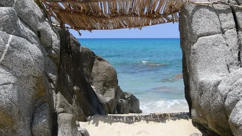 Makeshift hut between two rocks by the crystal clear sea Stock Footage 114066775