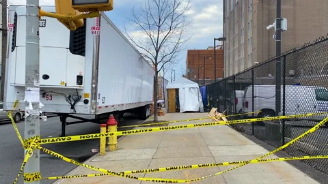 Makeshift morgue in refrigerated trailer behind yellow caution tape on sidewalk Video stock 137076710