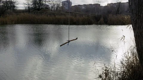 Makeshift Rope Swing Sways Gently Over a Calm River Stock Footage 325508422