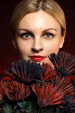 Makeup with arrows and red lips. Girl is looking from behind the flowers. Fotos de archivo