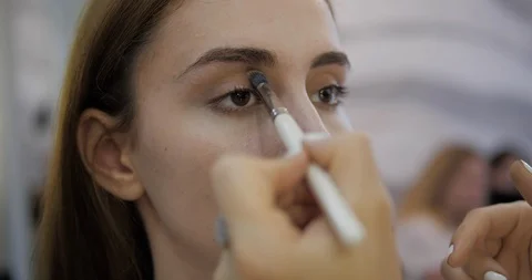 Makeup artist aligns concealer on young woman face closeup Stock Footage 124256486