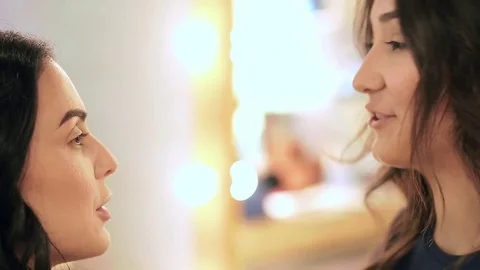 Makeup artist and a client laugh and chat during the session Stock Footage