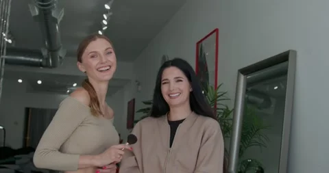 A makeup artist and her client are happily looking at the camera, posing and Vidéo 323241789