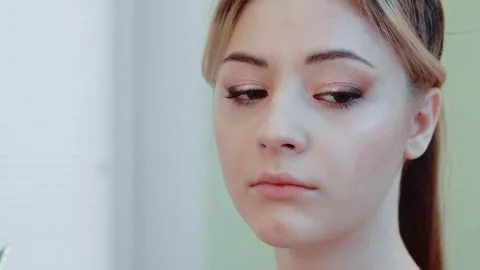 A makeup artist applies blush to the cheeks of a beautiful model with Stock Footage 149269381