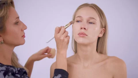 The makeup artist applies the foundation to the model. Stock Footage 142134945