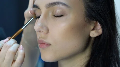 Makeup artist apply makeup to an attractive young women. Stock Footage 76139013