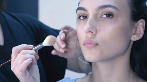 Makeup artist apply makeup to an attractive young women. Stock Footage 76139129