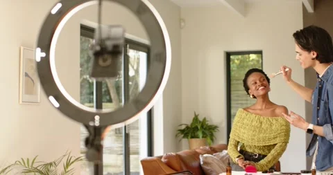 Makeup artist applying blush on African American woman in studio with ring Stock Footage 341393433