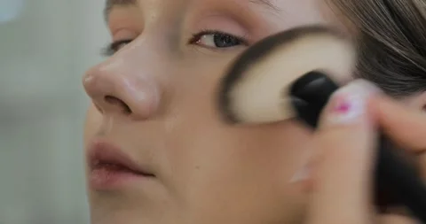 Makeup artist is applying blush bronzer with brush to young model cheek. Stock Footage 145502349