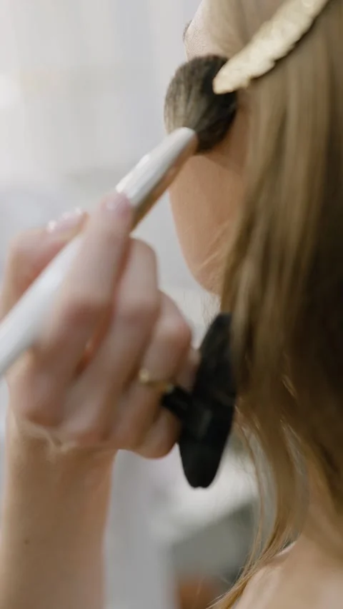 Makeup artist applying blush or highlighter to model face. Close-up vertical Stock-Footage 310998815