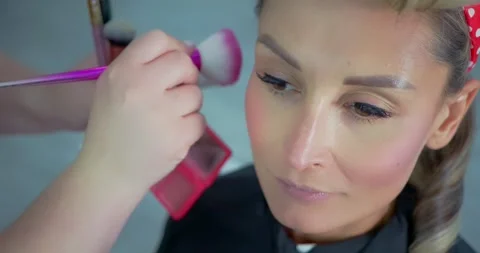 Makeup Artist Applying Blush on Woman's Face in Salon Stock Footage 323495711
