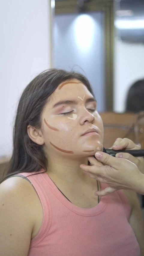 Makeup artist applying contour makeup on female client during beauty session Video stock 330377808