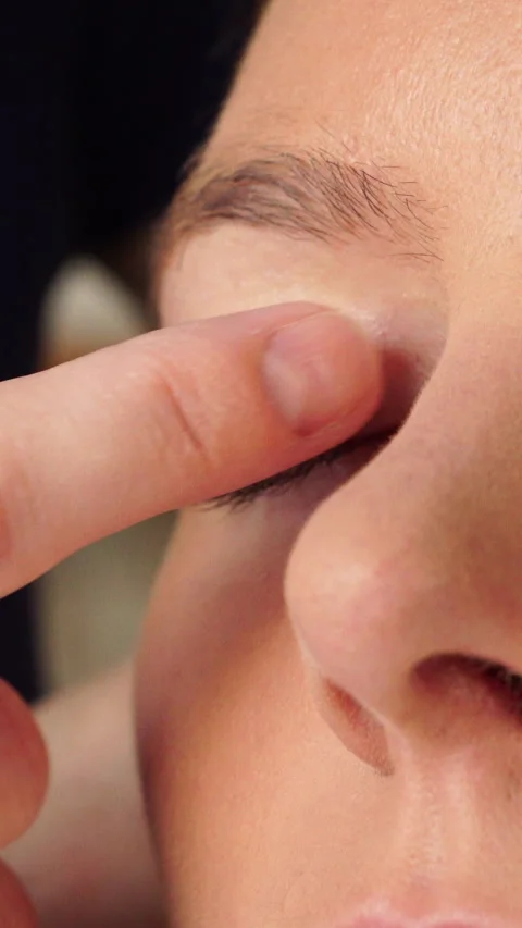 Makeup artist applying cream base to model eye. Vertical video Stock Footage 336430308