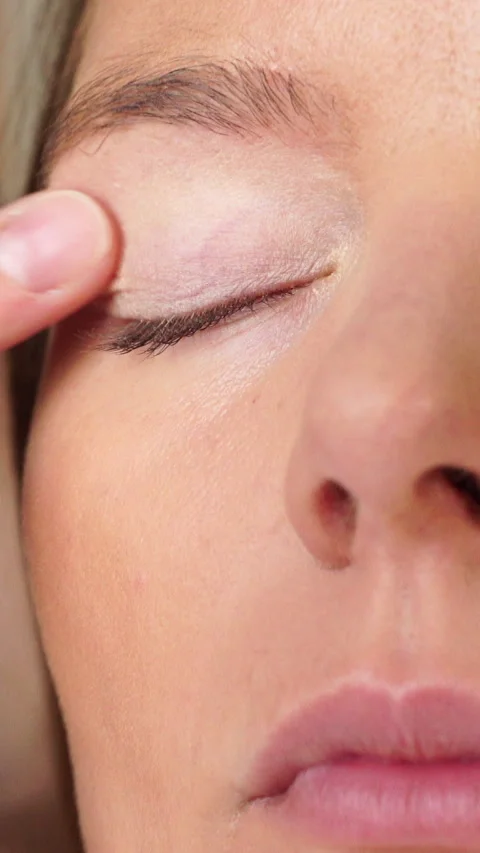 Makeup artist applying cream base to model eye. Vertical video Stock Footage 336430348