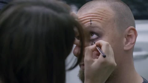 Makeup artist applying dark eyeshadow on rock or goth man for Halloween Stock Footage 305028015