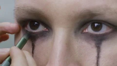 Makeup artist applying dark eyeshadow for Halloween goth rock look Stock Footage 305138243