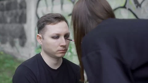 Makeup artist applying dark eyeshadow on rock goth men for Halloween Stock Footage 305138286