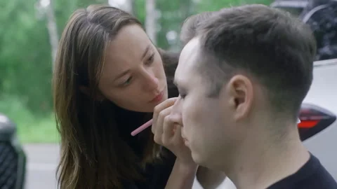 Makeup Artist Applying Dark Makeup to Man Outdoors Video stock 330921365