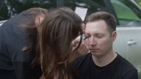 Makeup artist applying dark makeup to man outdoors Stock Footage 340651605