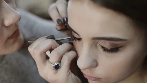Makeup artist applying false eyelashes to model's eyes Stock Footage 70663325