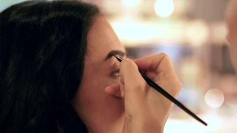 Makeup artist applying filling in eyebrows of a model with eyeshadows Stock Footage 76018690