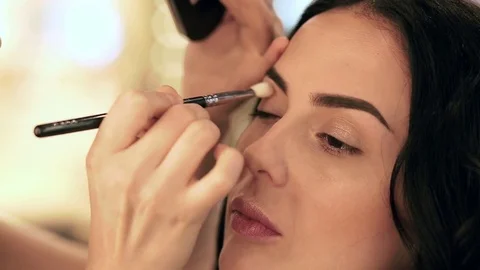 Makeup artist applying filling in eyebrows on a model with eyeshadows Stock Footage 76085891