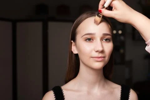 Makeup artist applying foundation on a model forehead Stock Photos
