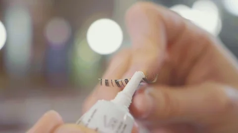 Makeup artist applying glue on the false eyelashes, closeup slow motion Stock Footage 82704024