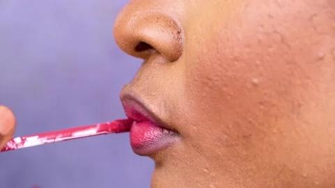 Makeup artist applying lipstick on lips of a model. Putting red lipstick on mode Stock Footage 217877315
