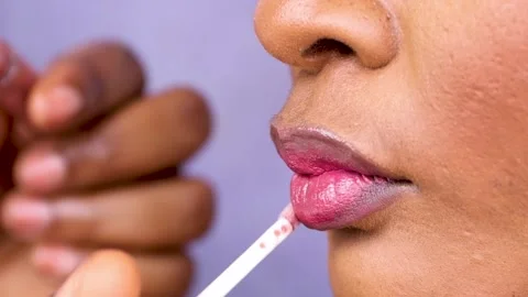 Makeup artist applying lipstick on lips of a model. Putting red lipstick on mode Stock-Footage 223434073