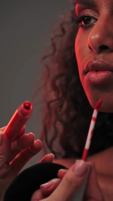 Makeup artist applying lipstick on the lips of a young attractive model in a Stock Footage 340331890